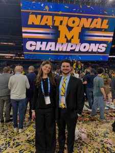 Two WCBN Sports broadcasters standing on the court covered in yellow and blue confetti.