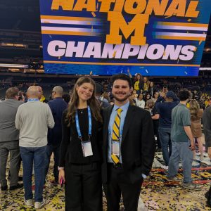 Two WCBN Sports broadcasters standing on the court covered in yellow and blue confetti.