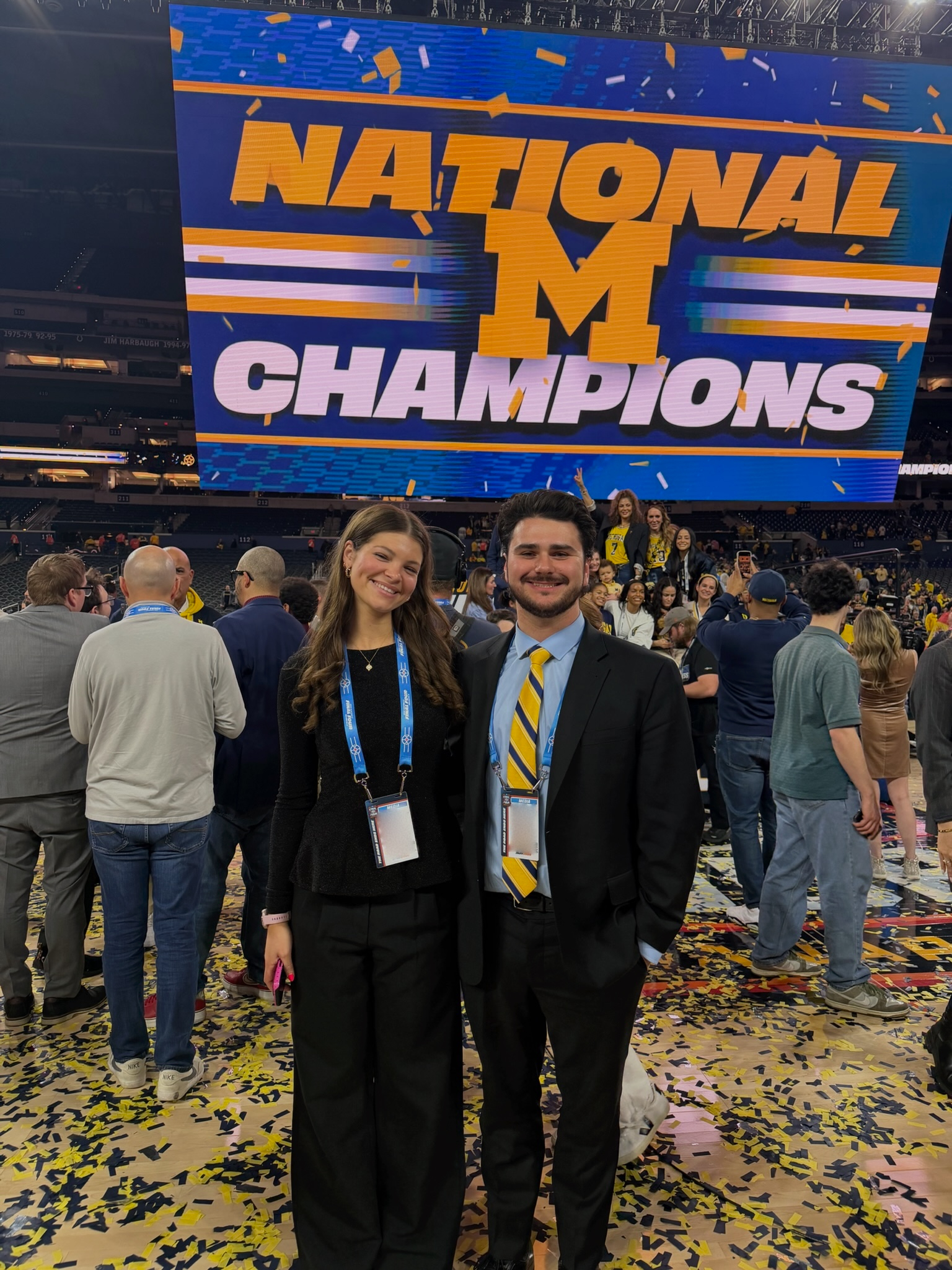 Two WCBN Sports broadcasters standing on the court covered in yellow and blue confetti.
